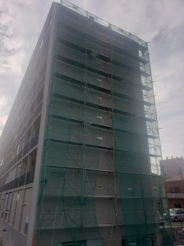 Immeuble sous échafaudage et filets verts, façade grise