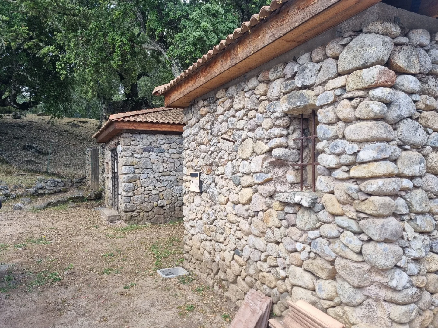 Bâtiment en pierre aux avant-toits en bois, avec un petit bâtiment attenant