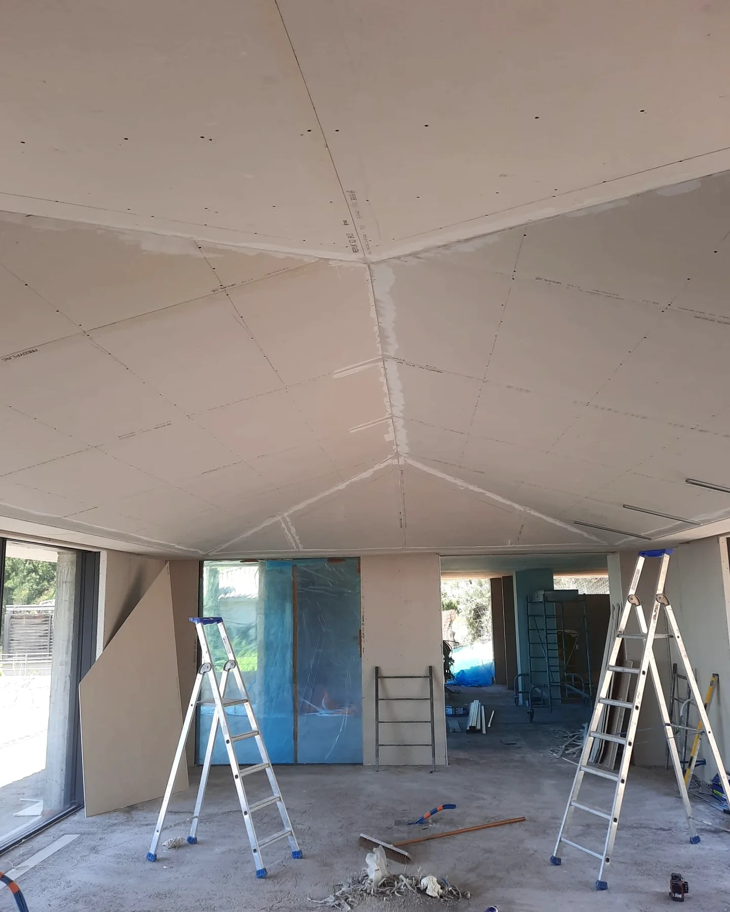 Faux plafond à quatre pans en plaques de plâtre, joints bandés, dans un volume aux grandes baies vitrées