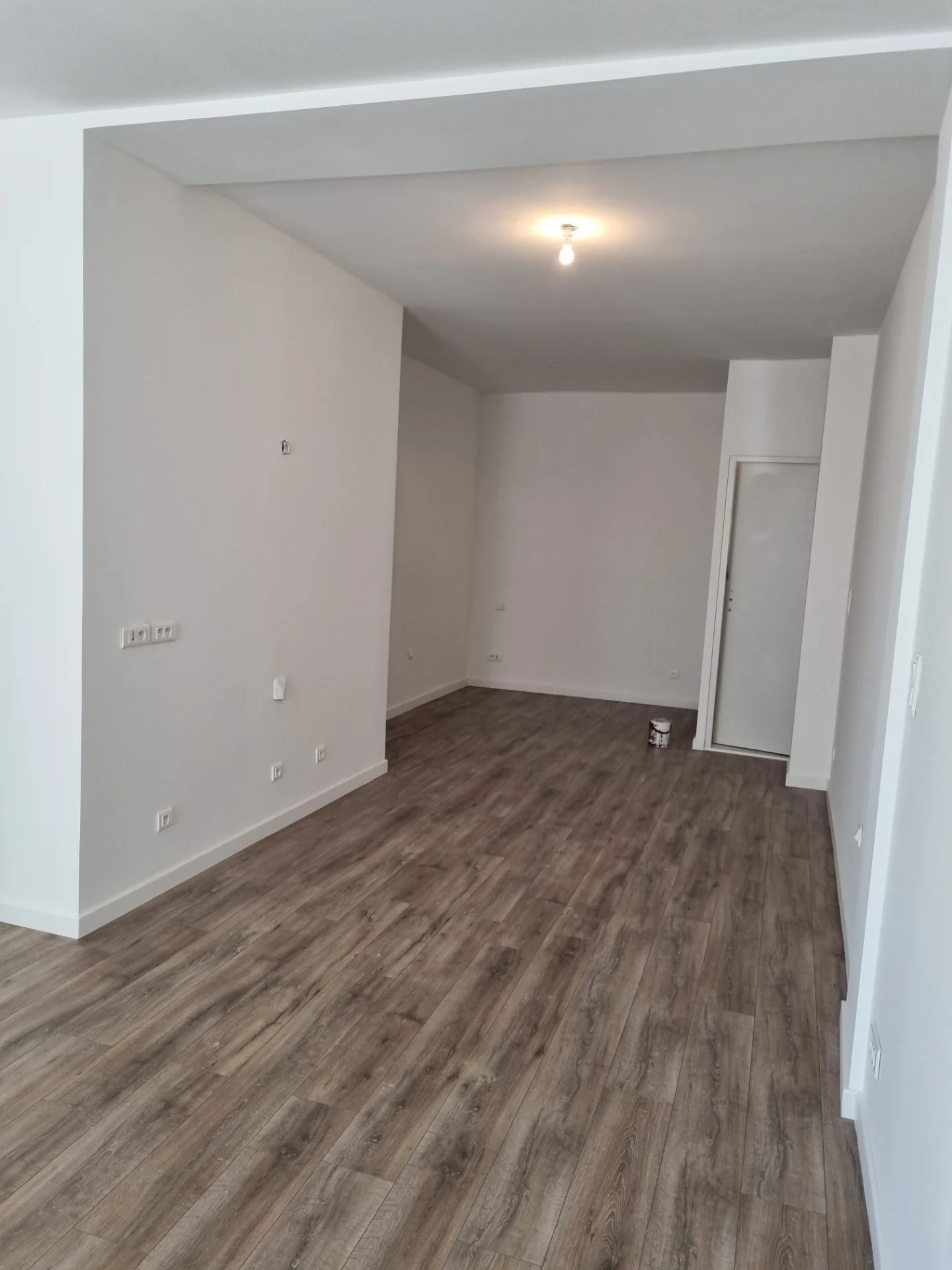 Local commercial rénové, vue vers le fond avec une porte blanche et un retour de mur