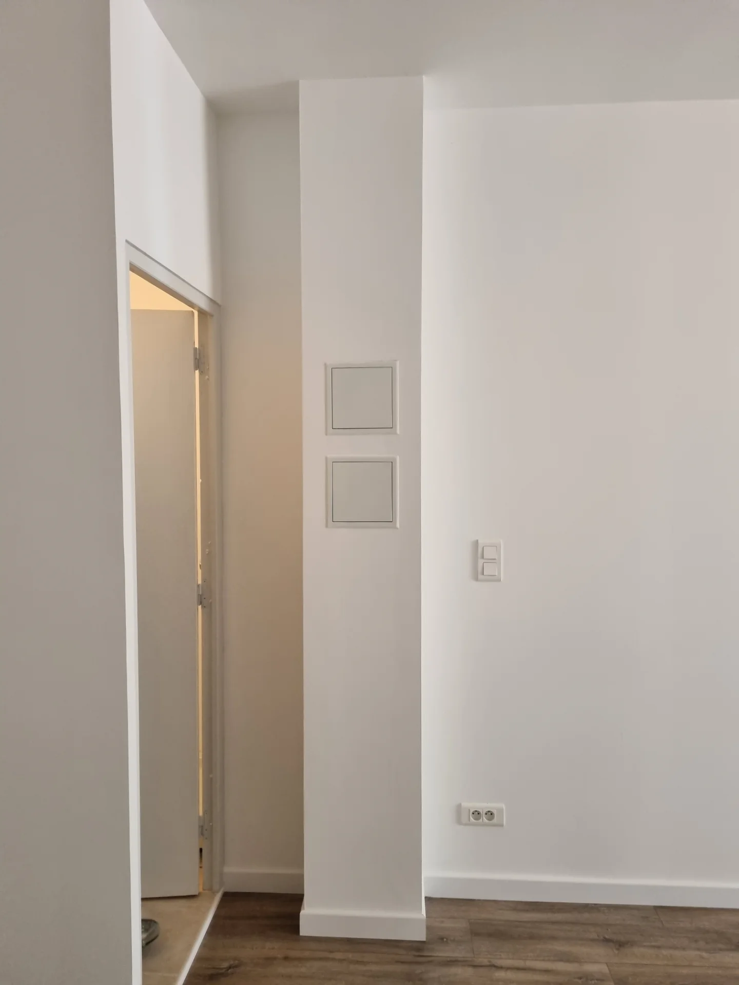 Mur blanc avec les deux trappes d’accès refermées, interrupteur et prise