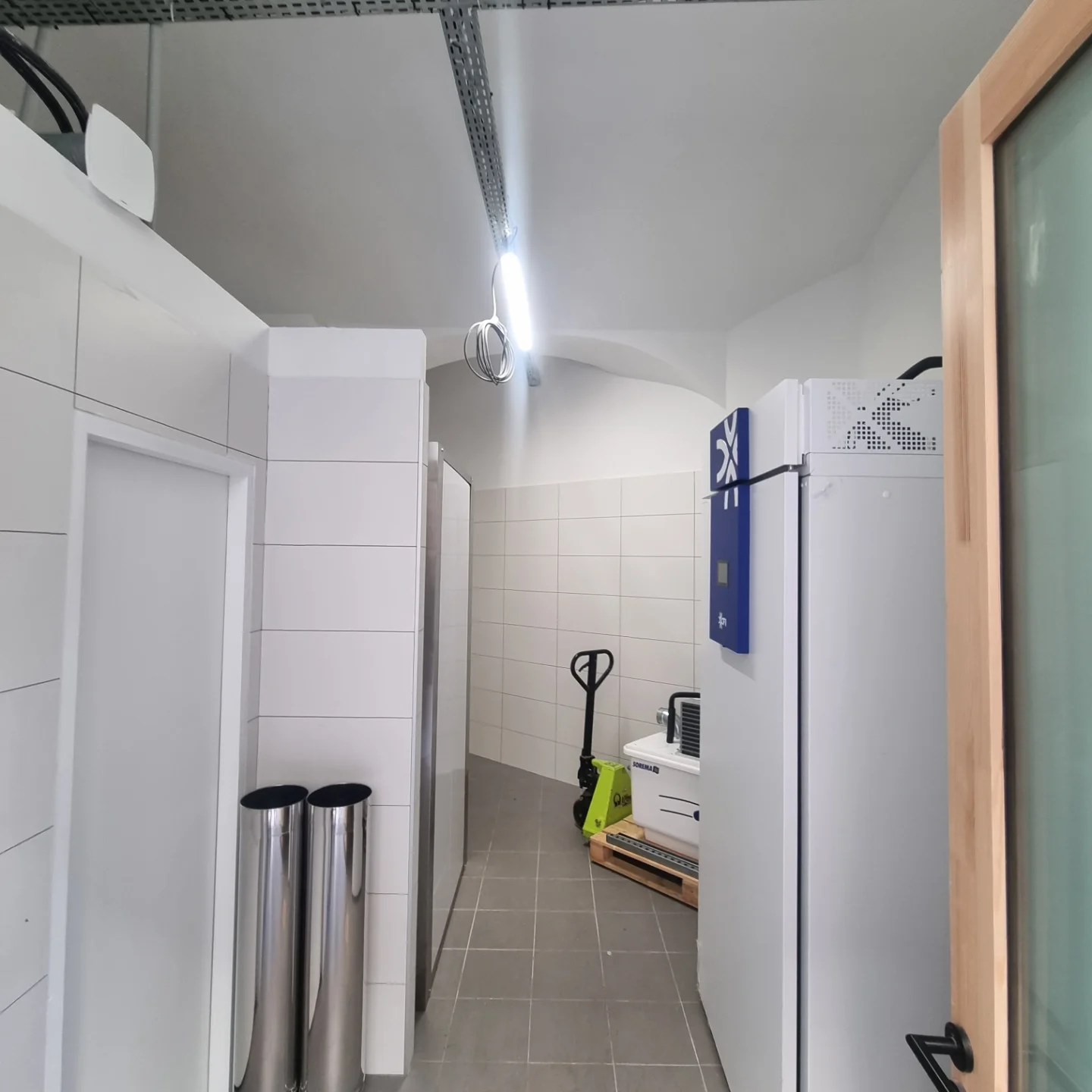 Intérieur du local sous voûte, murs et plafond blancs, carrelage au sol