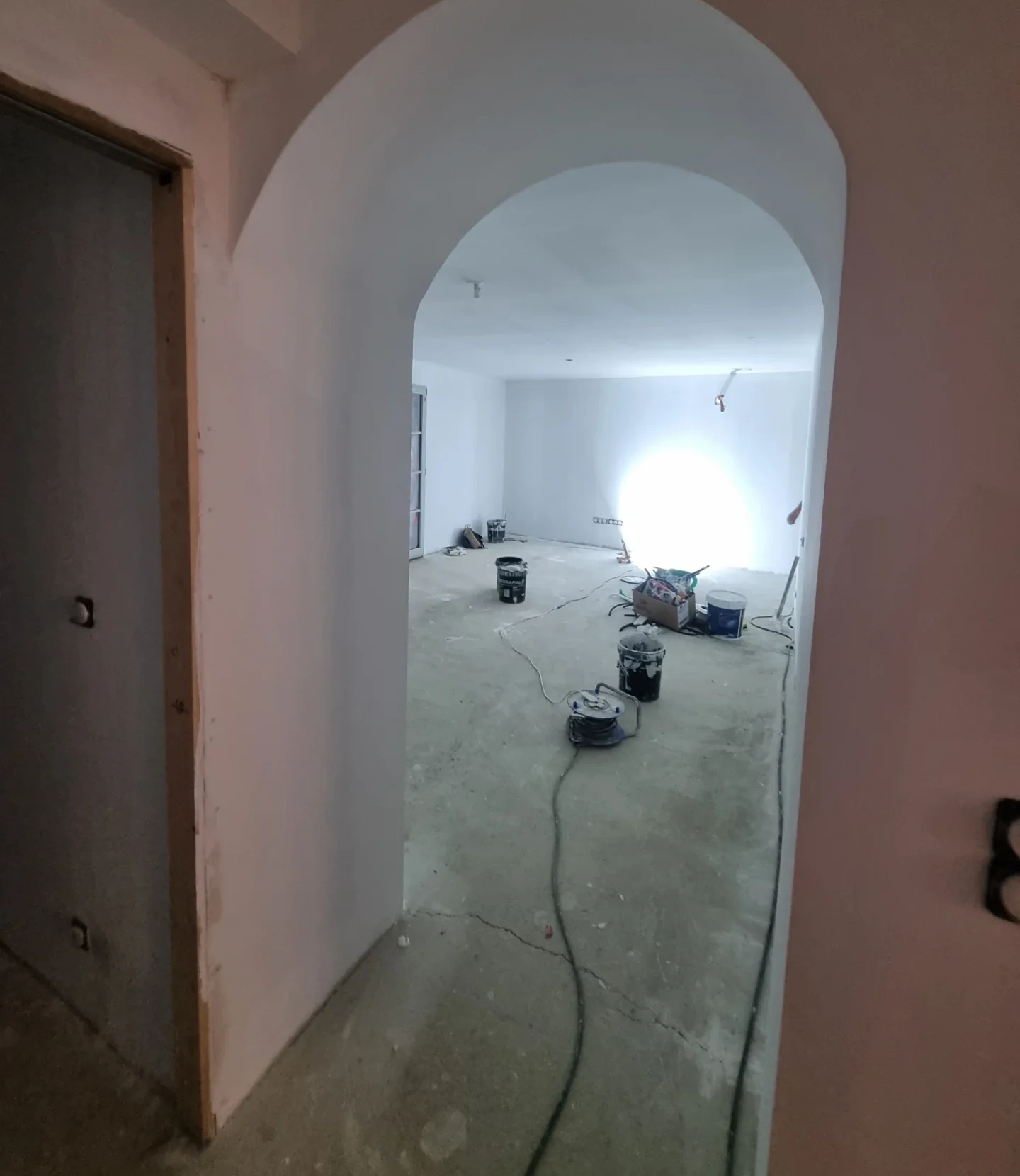 Arche enduite ouvrant sur un séjour en chantier